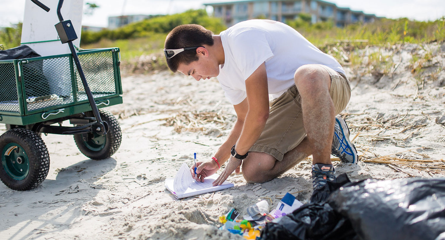 Student collecting samples on a beach.