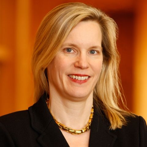 Headshot of a blond woman wearing a gold necklace and black blazer