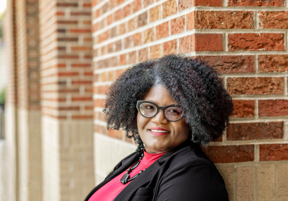 woman stands outside with a brick wall in the background
