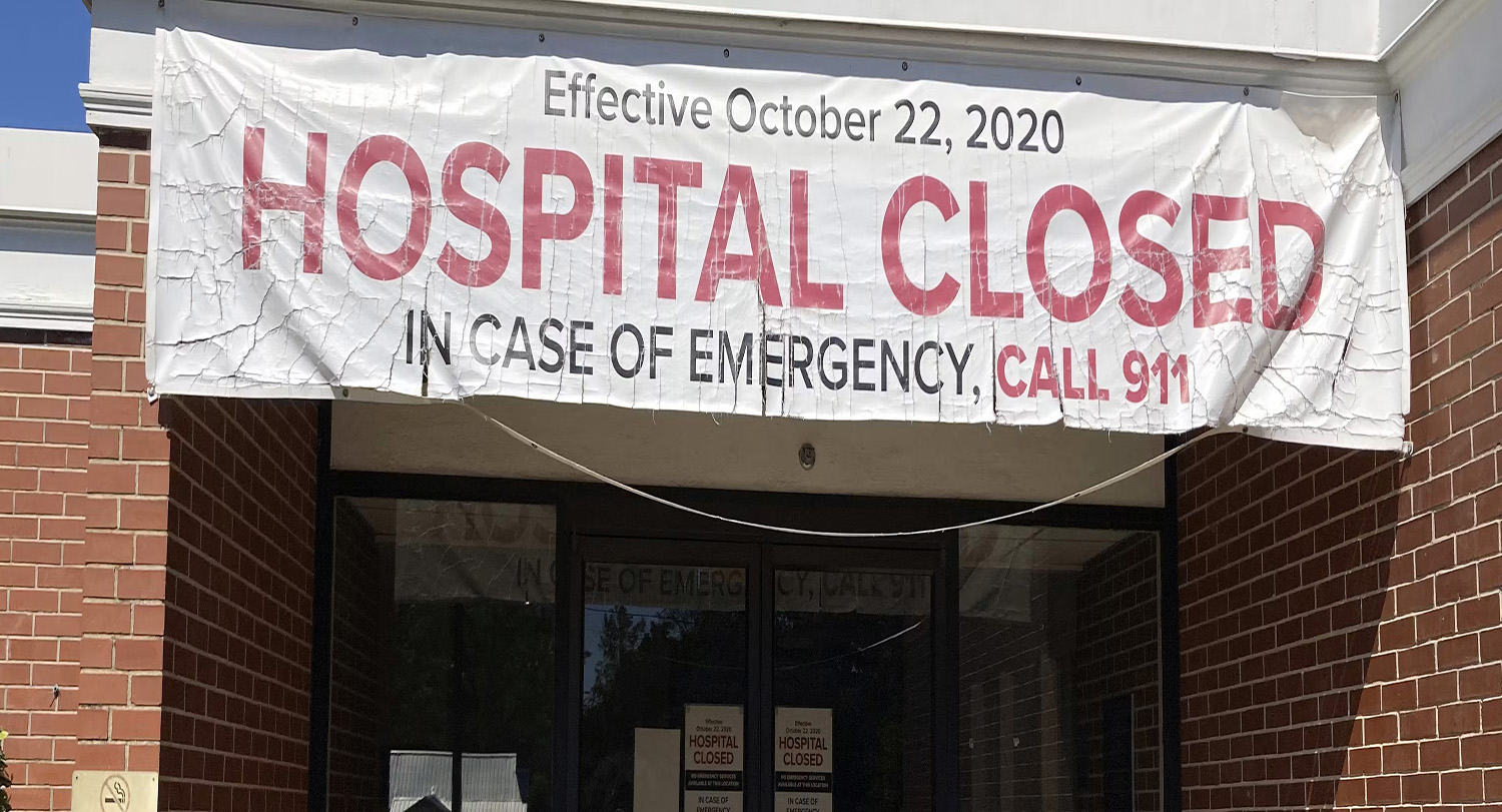 A banner hangs outside a building with the message "HOSPITAL CLOSED"