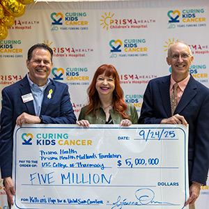 Curing Kids Cancer founders Clay and Grainne Owen present a check to Michael Wyatt from the USC College of Pharmacy