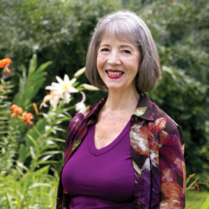 Sarah Barker smiles for the camera with flowers in the background.