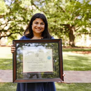 woman in blue dress holding framed award