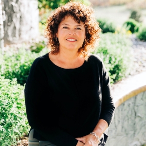 Jane Roberts smiles in front of foliage
